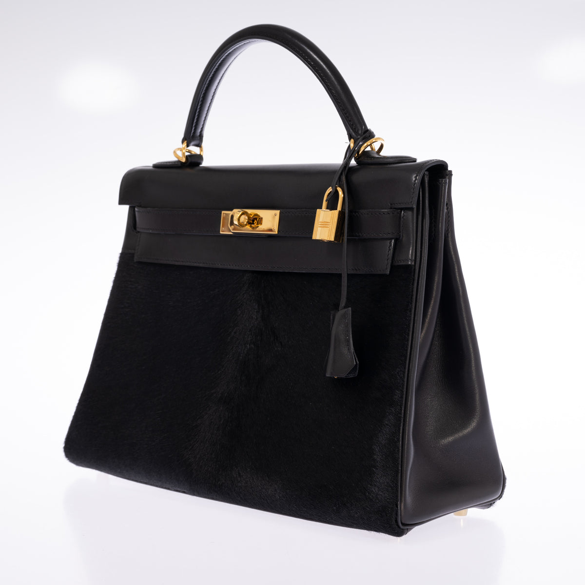 Hermès Kelly 32 Noir Box leather and pony skin with Gold hardware, three-quarter front view showing the right gusset and clochette.