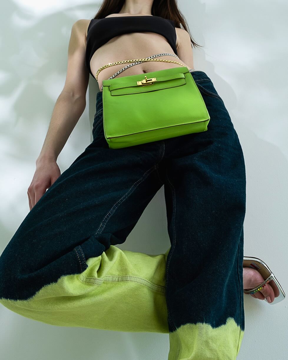 Hermès Kelly Danse Apple Green Swift Gold Hardware, worn at the waist on a chain by a model