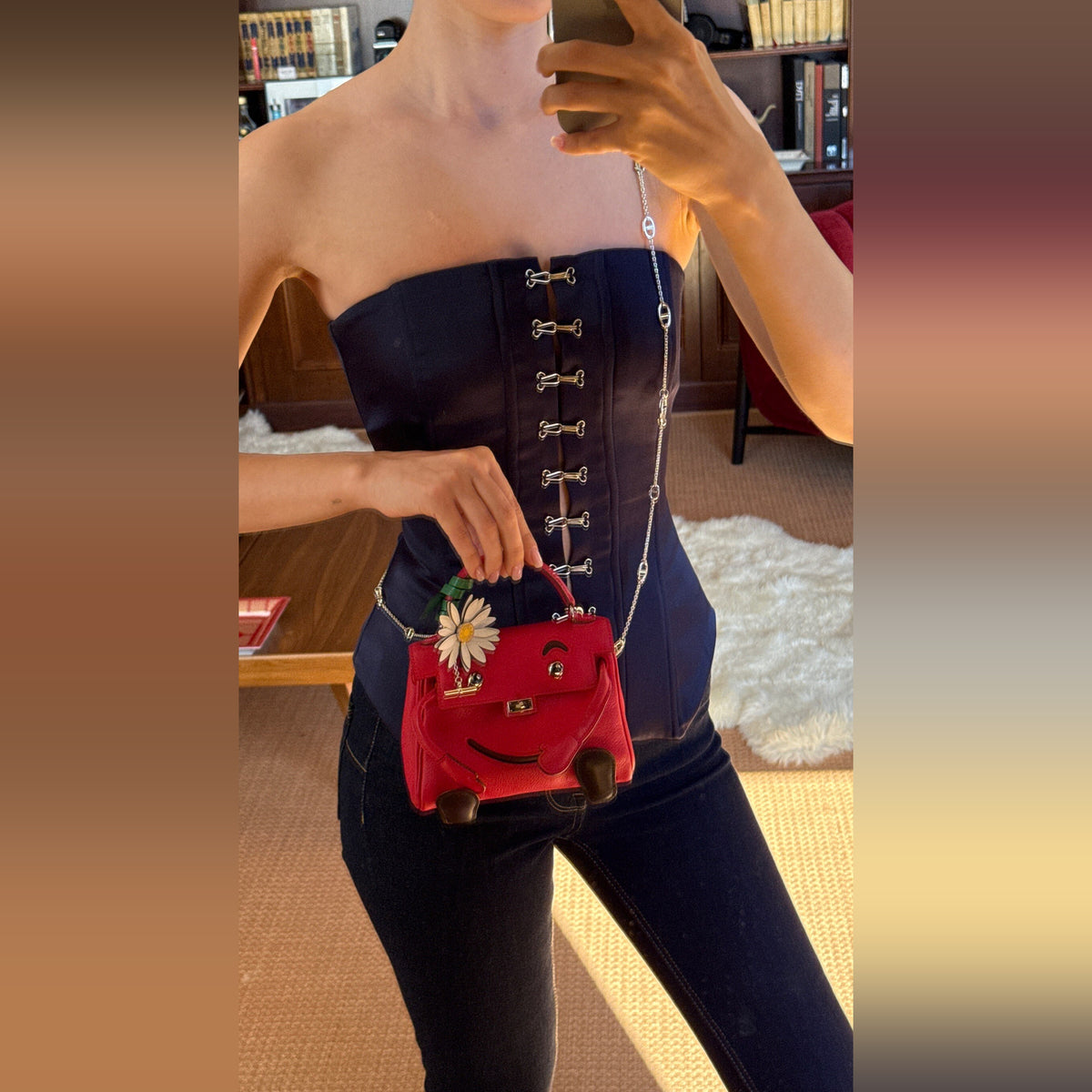 Hermès Kelly Doll Quelle Idole Rouge Vif Gulliver Palladium Hardware, carried by a model with a marguerite charm on the handle, charm sold separately