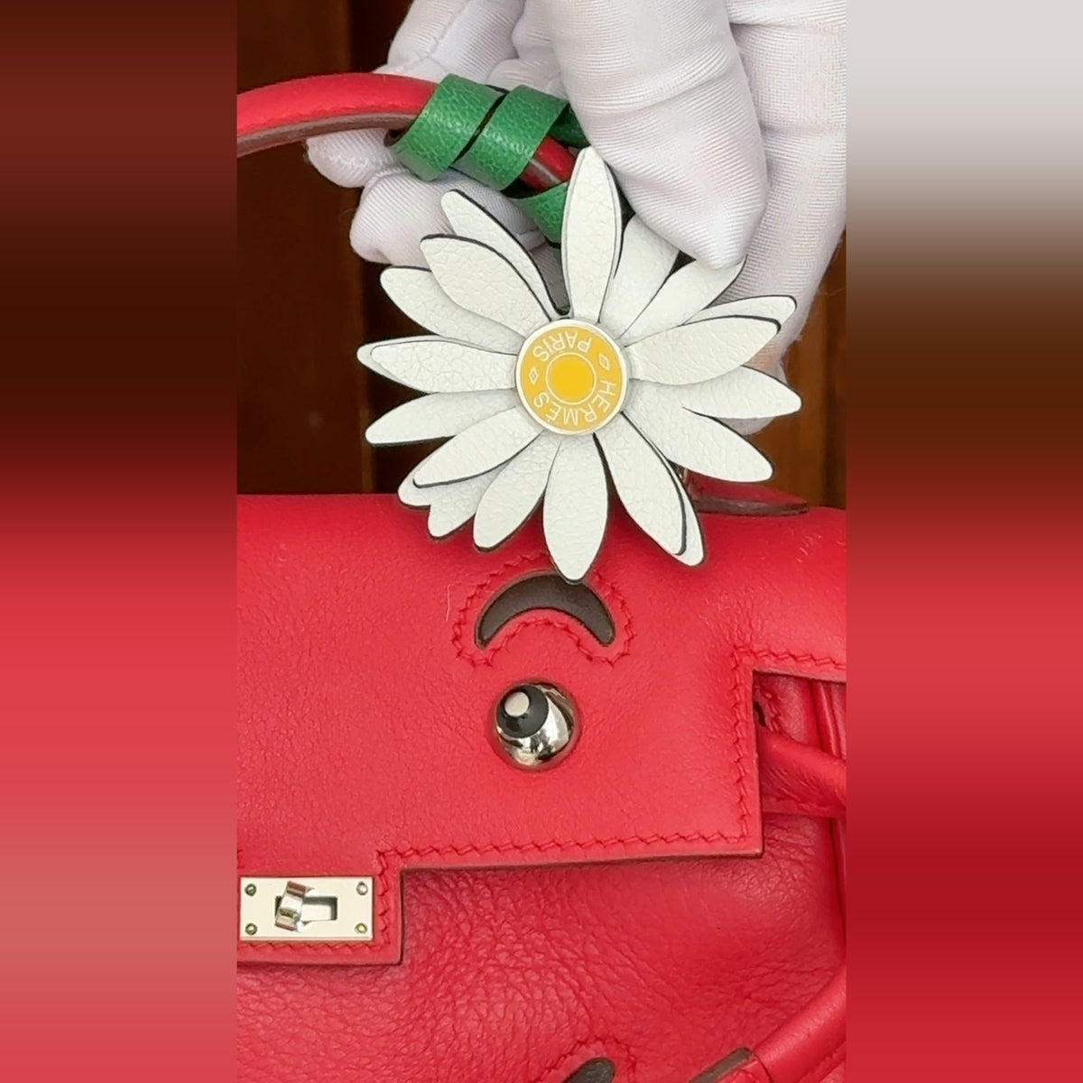 Hermès Kelly Doll Quelle Idole Rouge Vif Gulliver Palladium Hardware, close view of the face detail with a marguerite charm on the handle, charm sold separately
