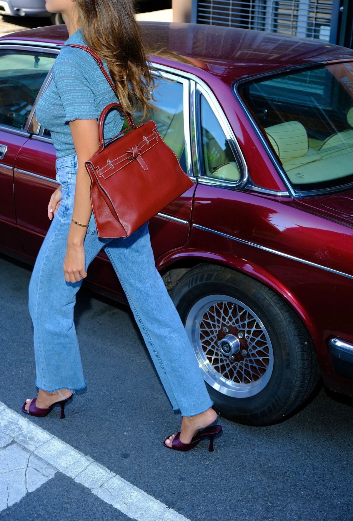 Hermès Kelly Flat 35 Rouge H Swift Palladium Hardware, carried on the shoulder by a model walking past a car