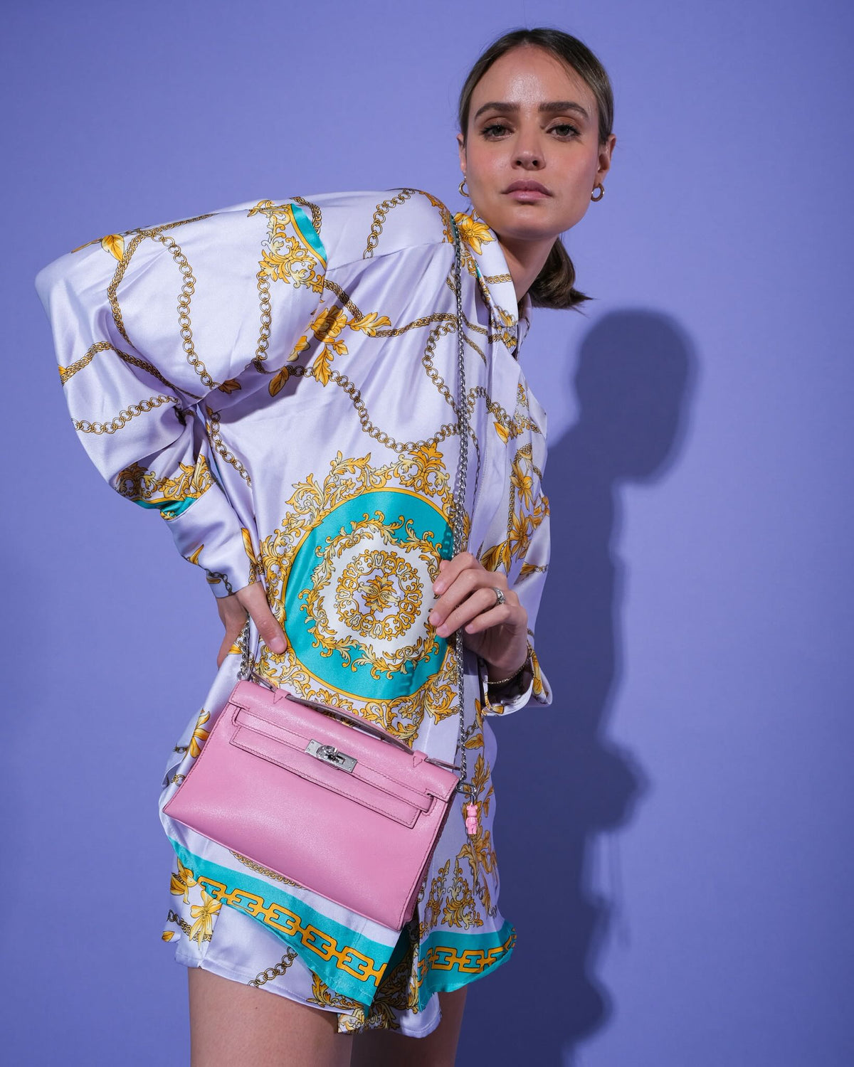 Hermès Kelly Pochette 5P Swift with Palladium Hardware, worn crossbody on a chain by a model, with a bear charm