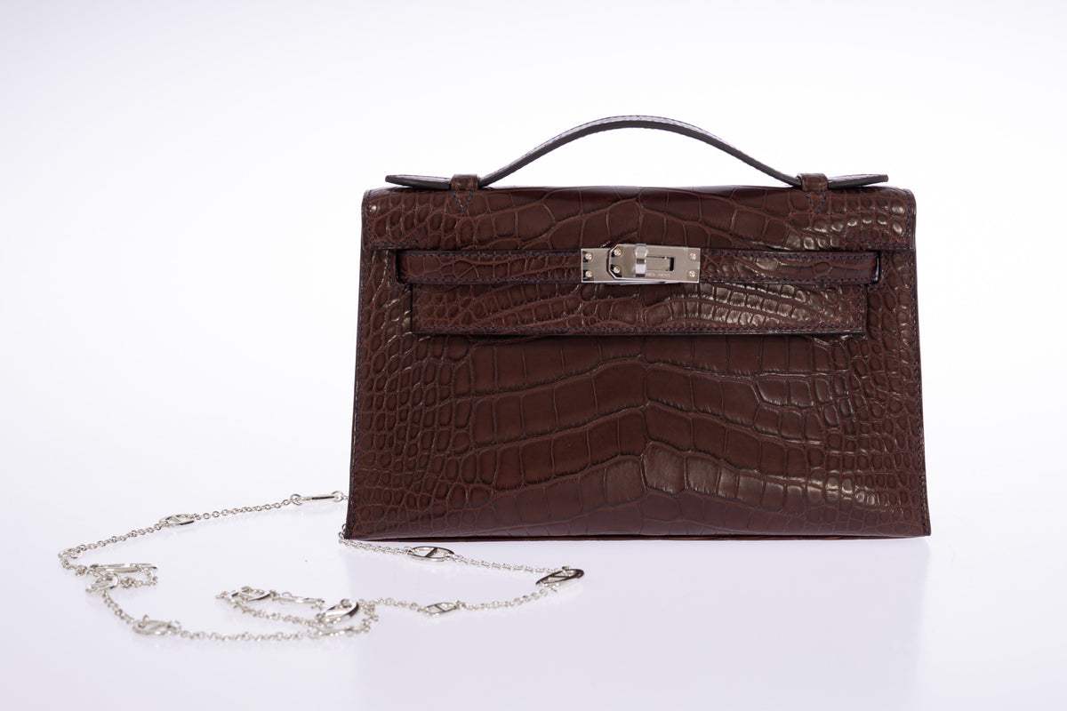 Hermès Kelly Pochette in Havane matte alligator, front view with a silver chain.