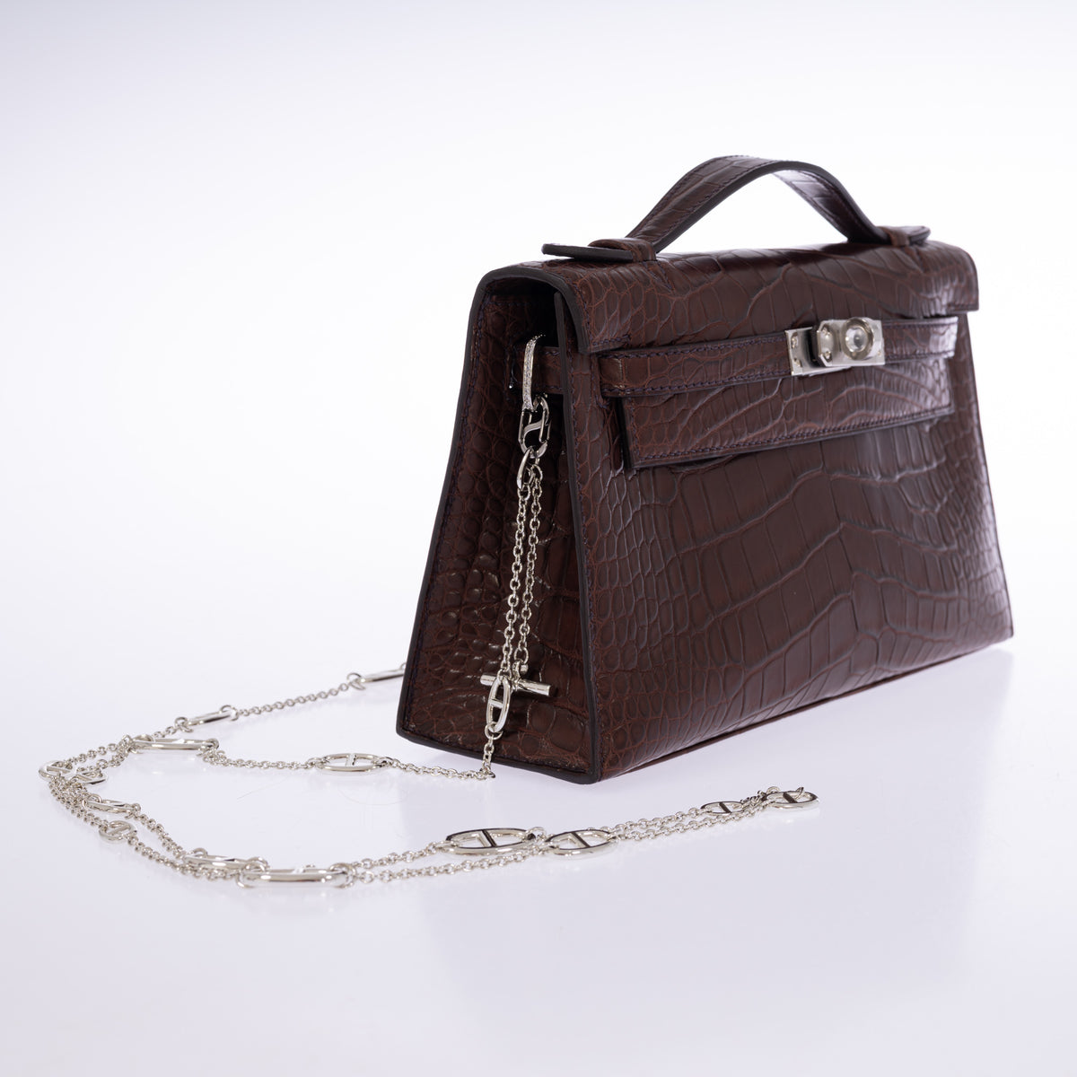 Hermès Kelly Pochette in Havane matte alligator, left three-quarter view with chain attached.