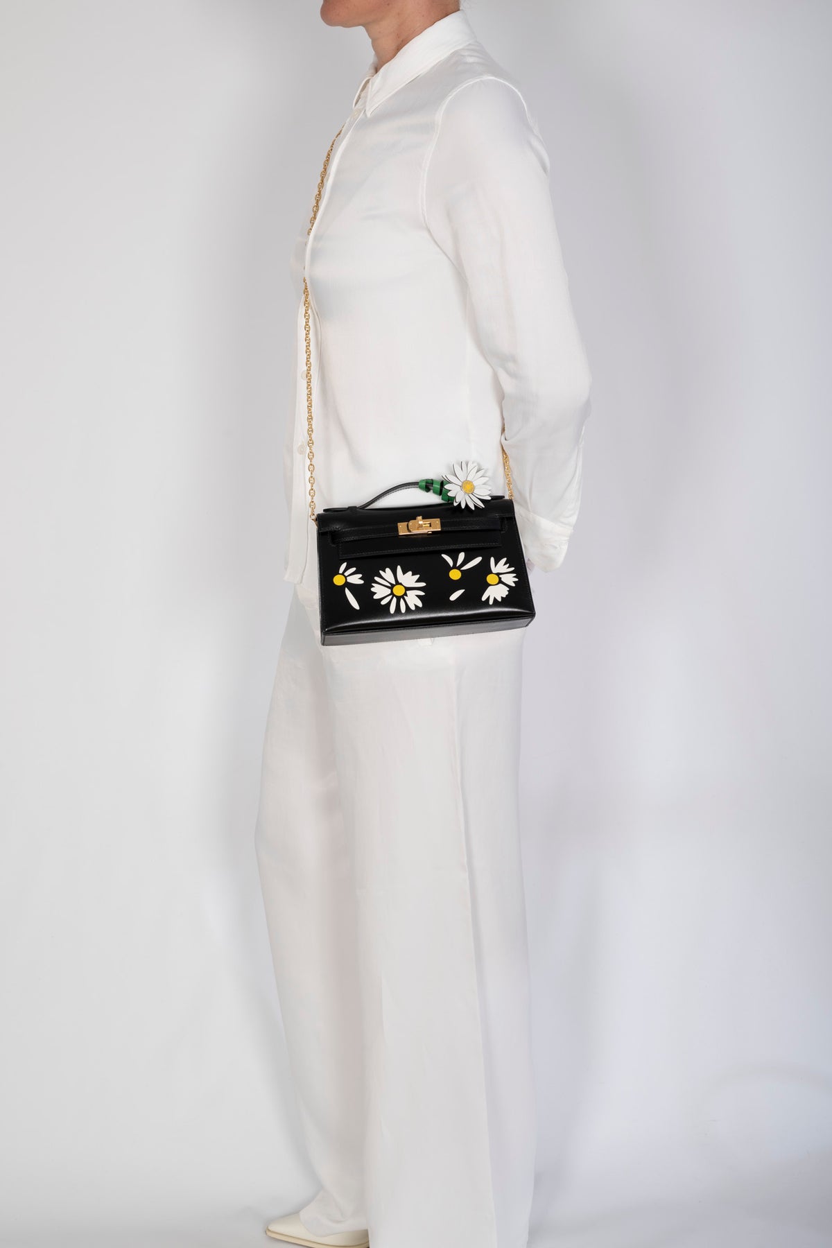Hermès Kelly Pochette Marqueterie Marguerite Noir Box Gold Hardware, held at the side by a model