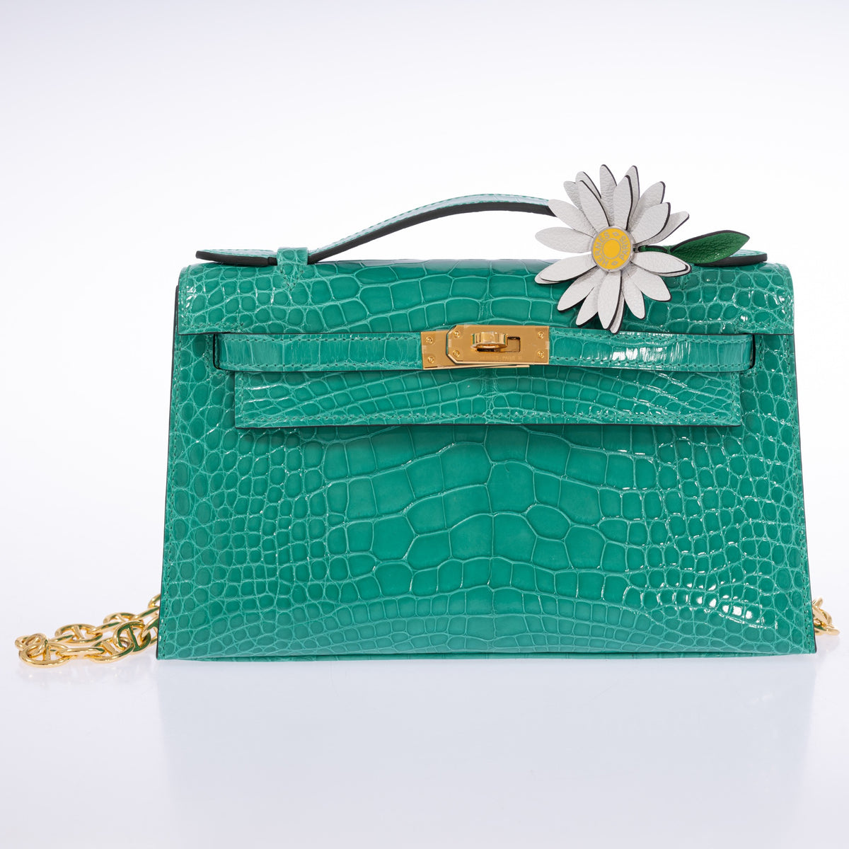 Hermès Kelly Pochette in Vert Jade shiny alligator with gold hardware, styled with a white daisy charm.