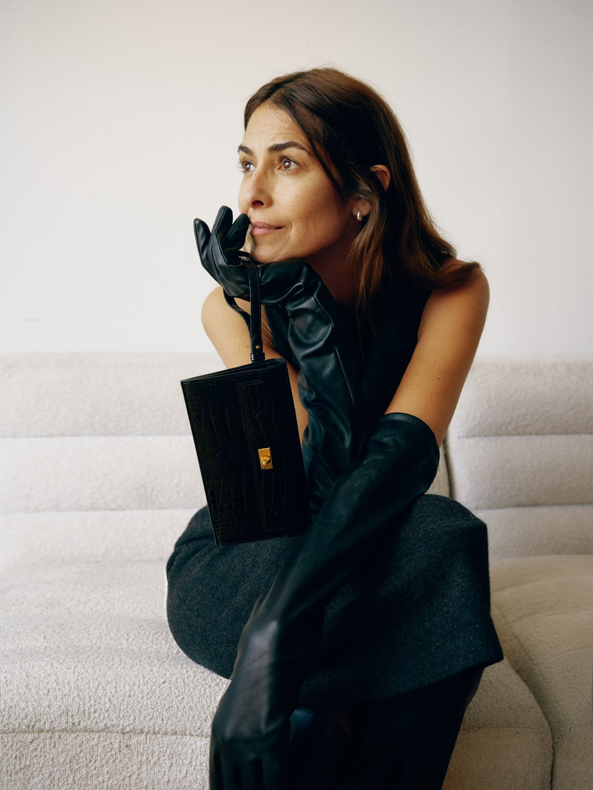 Hermès Kelly Pocket Long Wallet Black Alligator Gold Hardware, held by a seated model in long gloves