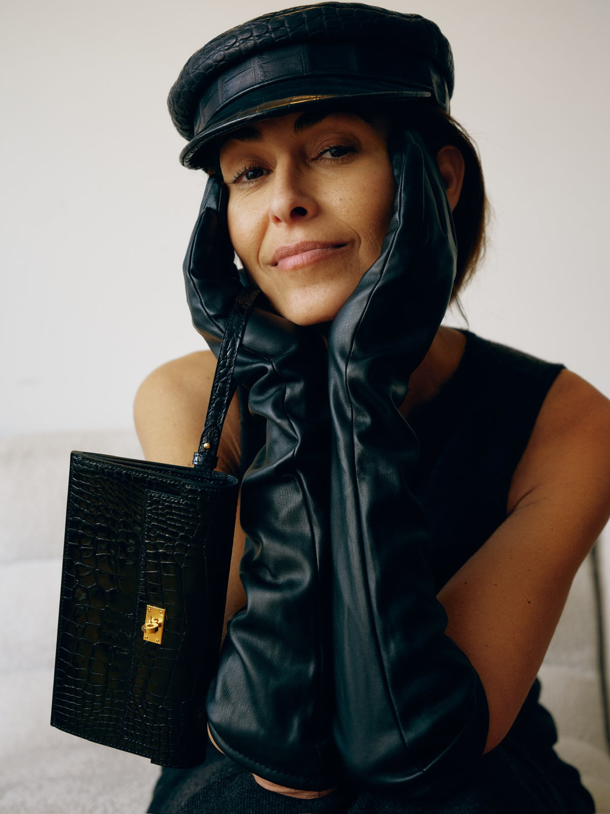Hermès Kelly Pocket Long Wallet Black Alligator Gold Hardware, held by a model in a leather cap, close view