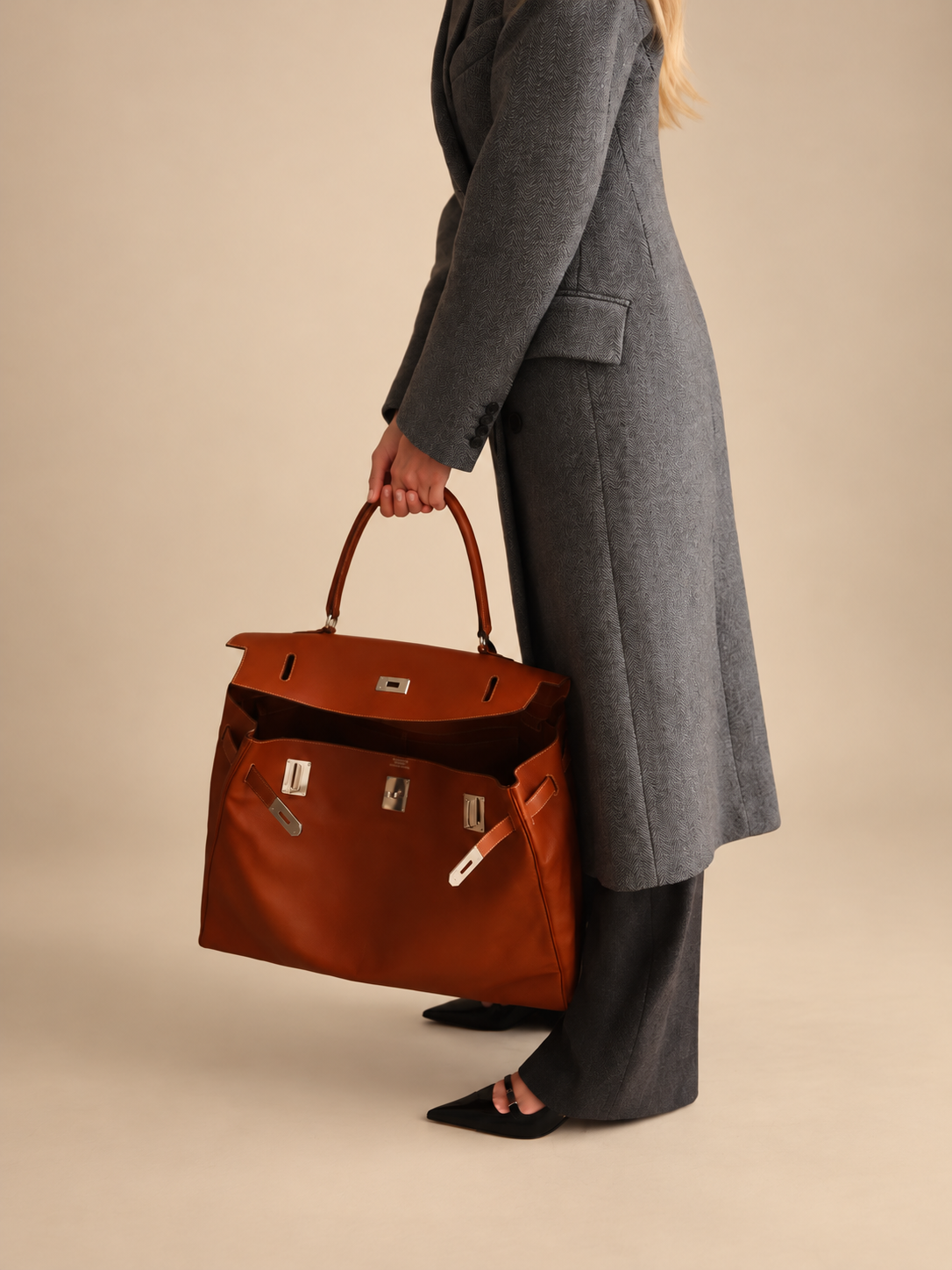 Hermès Kelly Relax 50 Fauve Swift Palladium Hardware, carried by hand with the flap open, front close view
