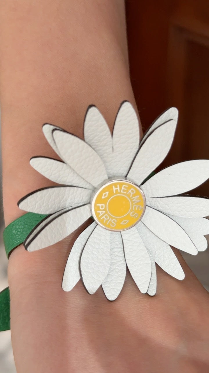Hermès Marguerite Daisy Charm White Jaune de Naples Bambou, close view of the yellow Clou de Selle center engraved Hermès Paris, worn on the wrist