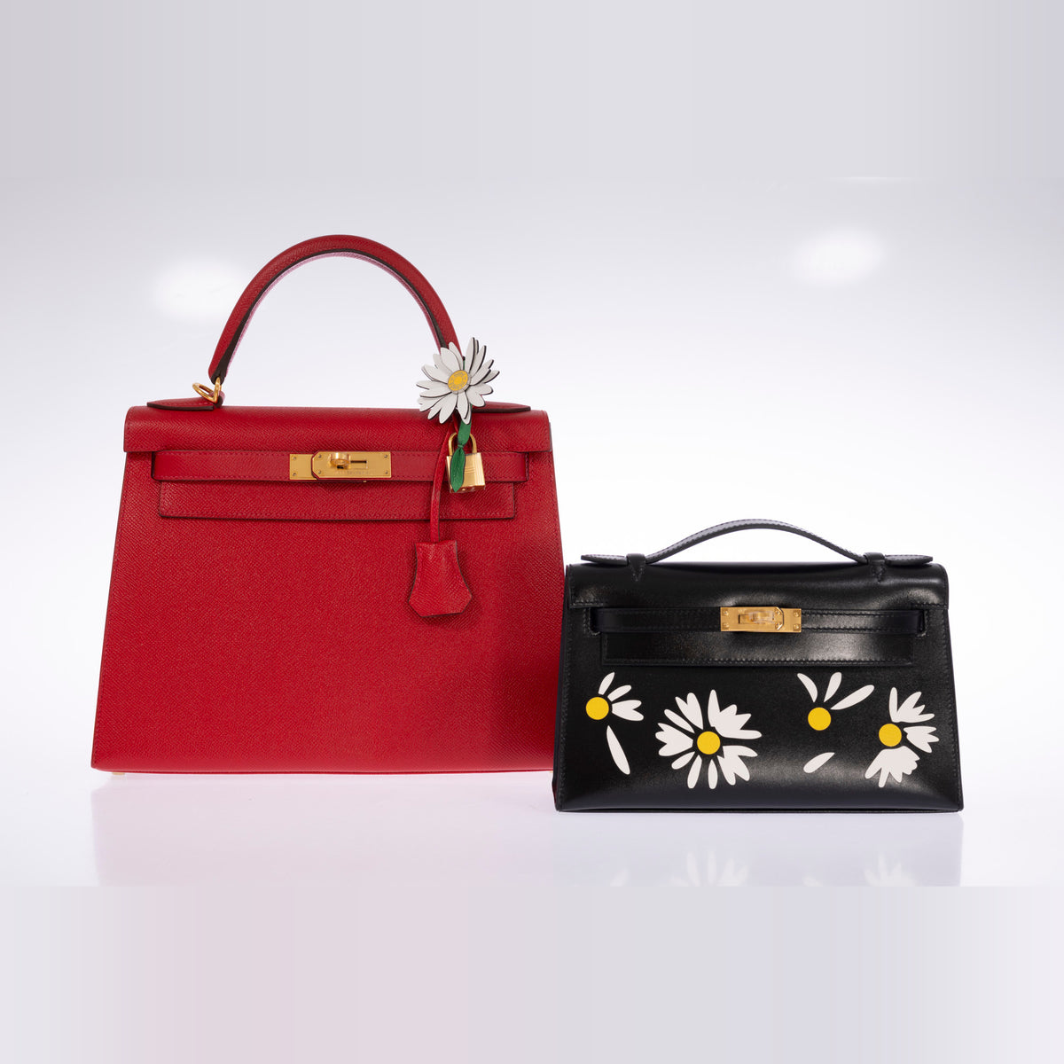 Hermès Marguerite Daisy Charm White Jaune de Naples Bambou, on the handle of a red Kelly Sellier shown beside a Kelly Pochette, bags sold separately
