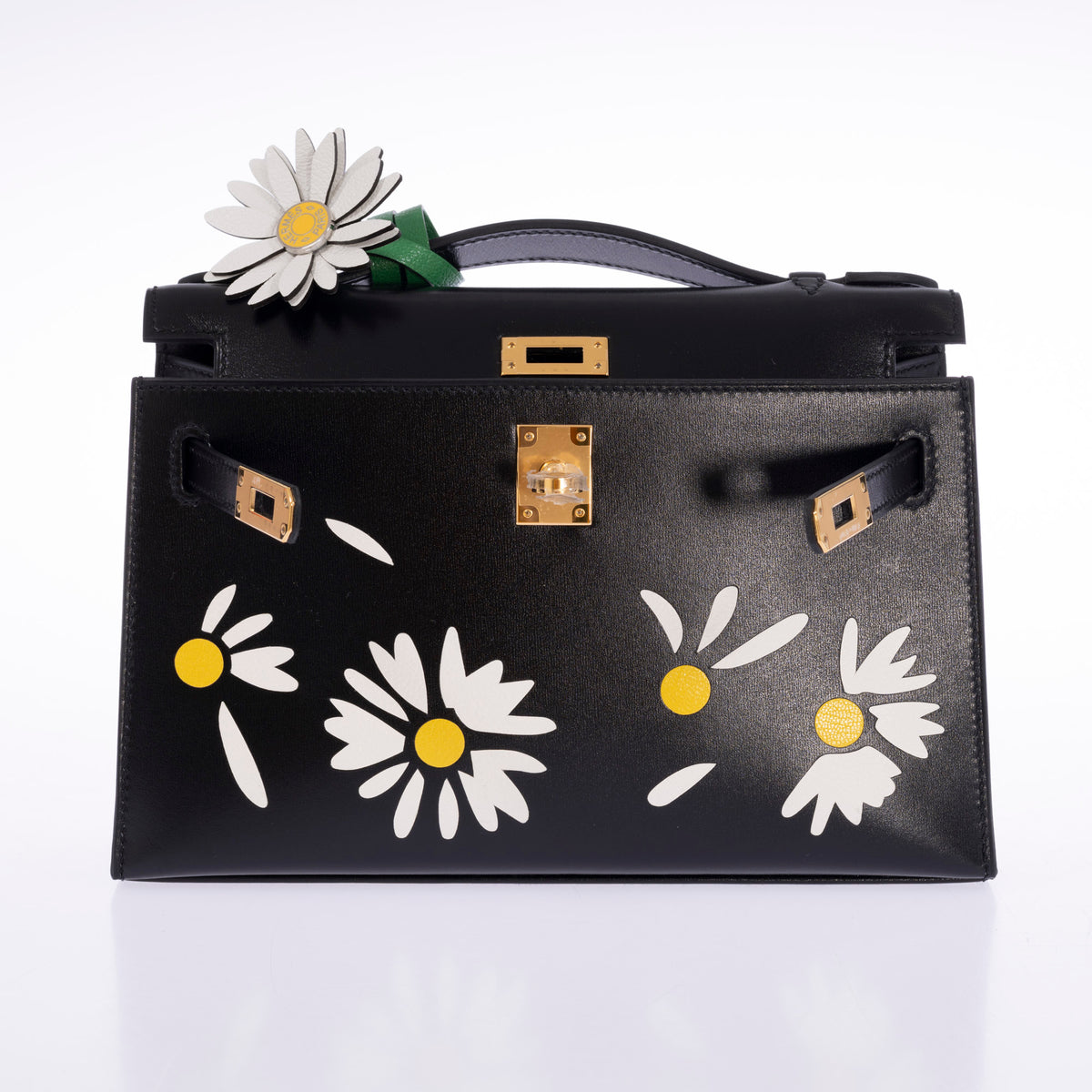 Hermès Marguerite Daisy Charm White Jaune de Naples Bambou, clipped to the handle of a Kelly Pochette, bag sold separately