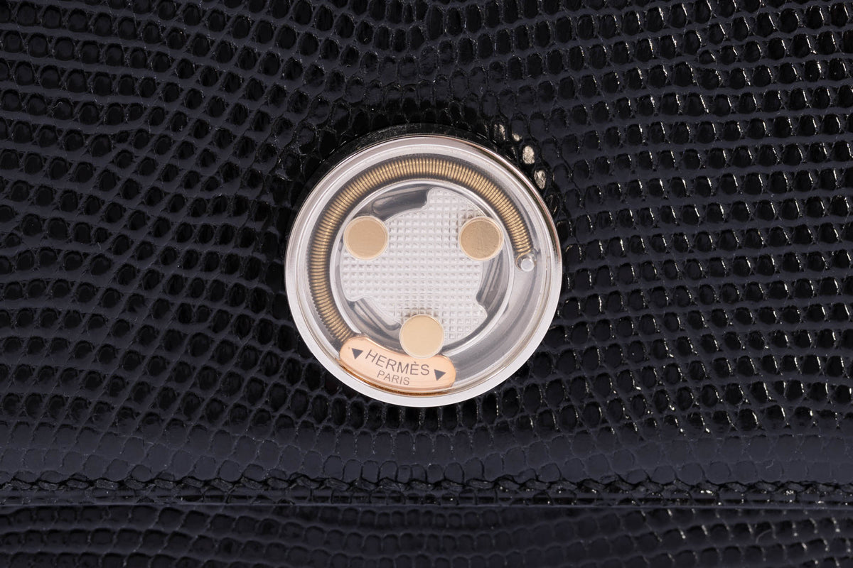 Close-up of the Hermès Minuit au Faubourg clasp: palladium case and textured plate with gold studs, a gold spring and a gold HERMÈS PARIS plaque under a crystal.