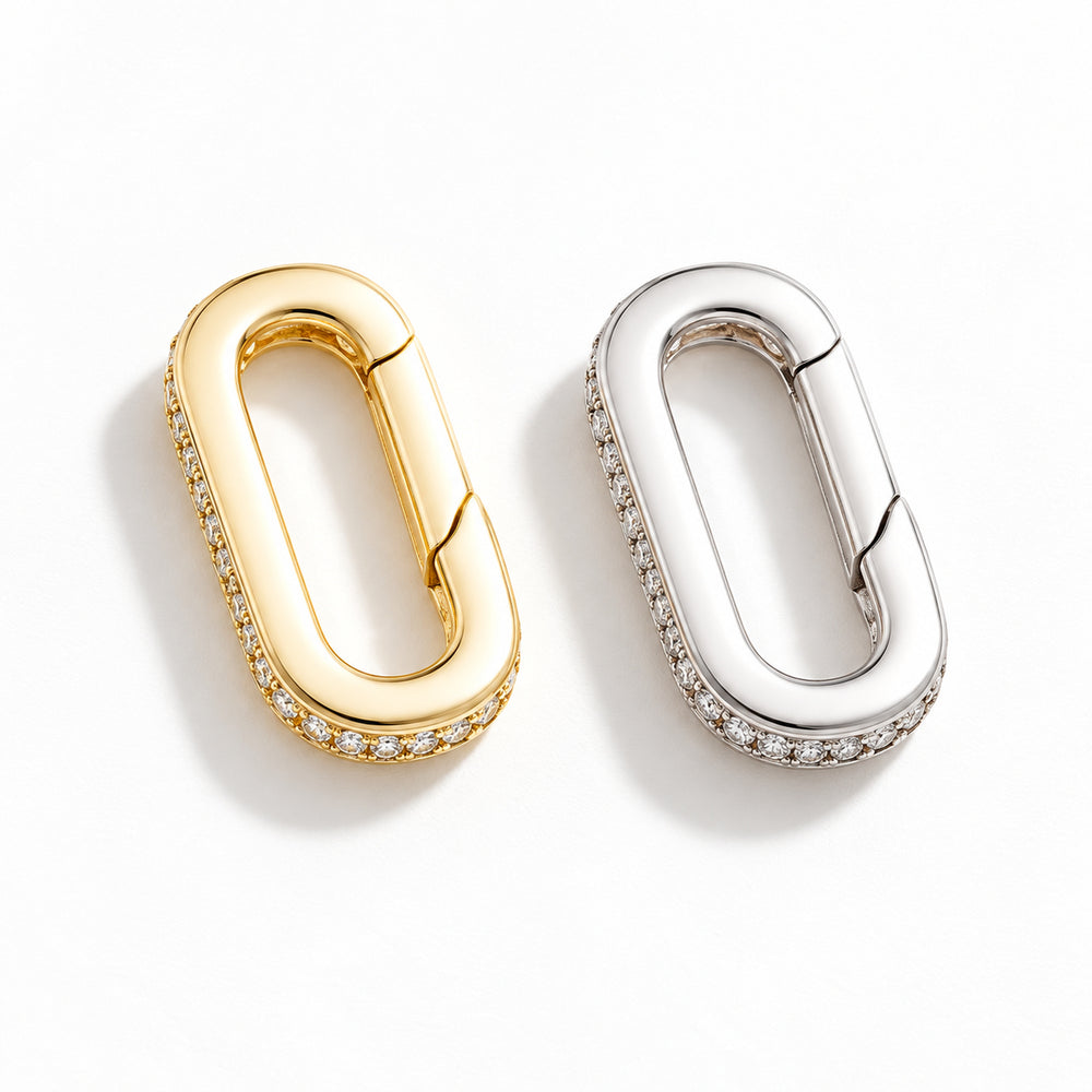 The Strap Converter, a mixed pair of oval spring-gate converters in gold and palladium tone with clear stone detailing, on white.