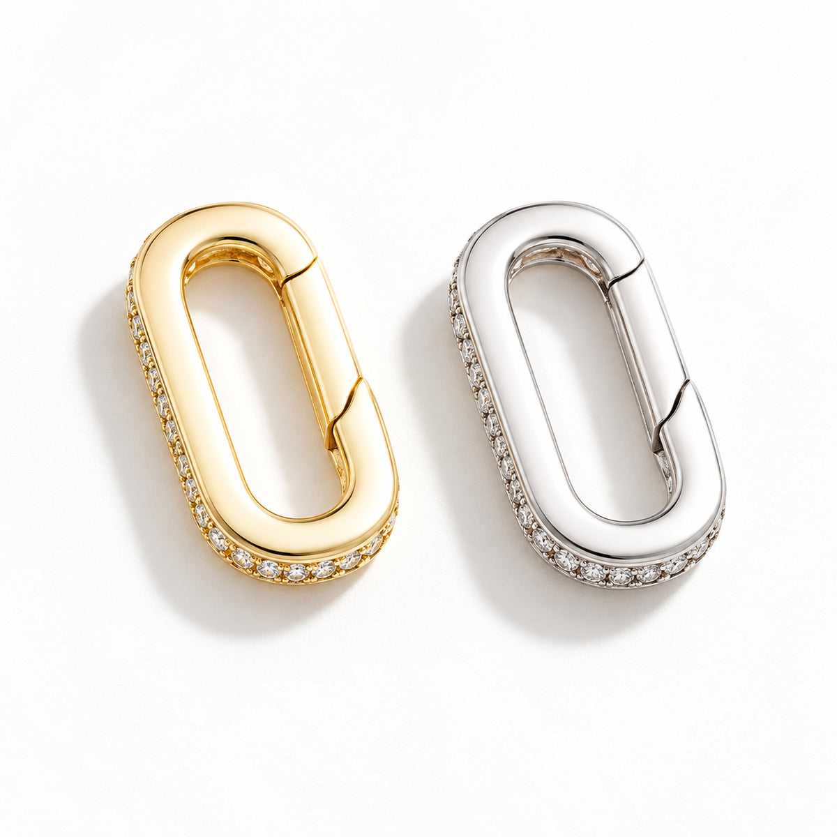 The Strap Converter, a mixed pair of oval spring-gate converters in gold and palladium tone with clear stone detailing, on white.