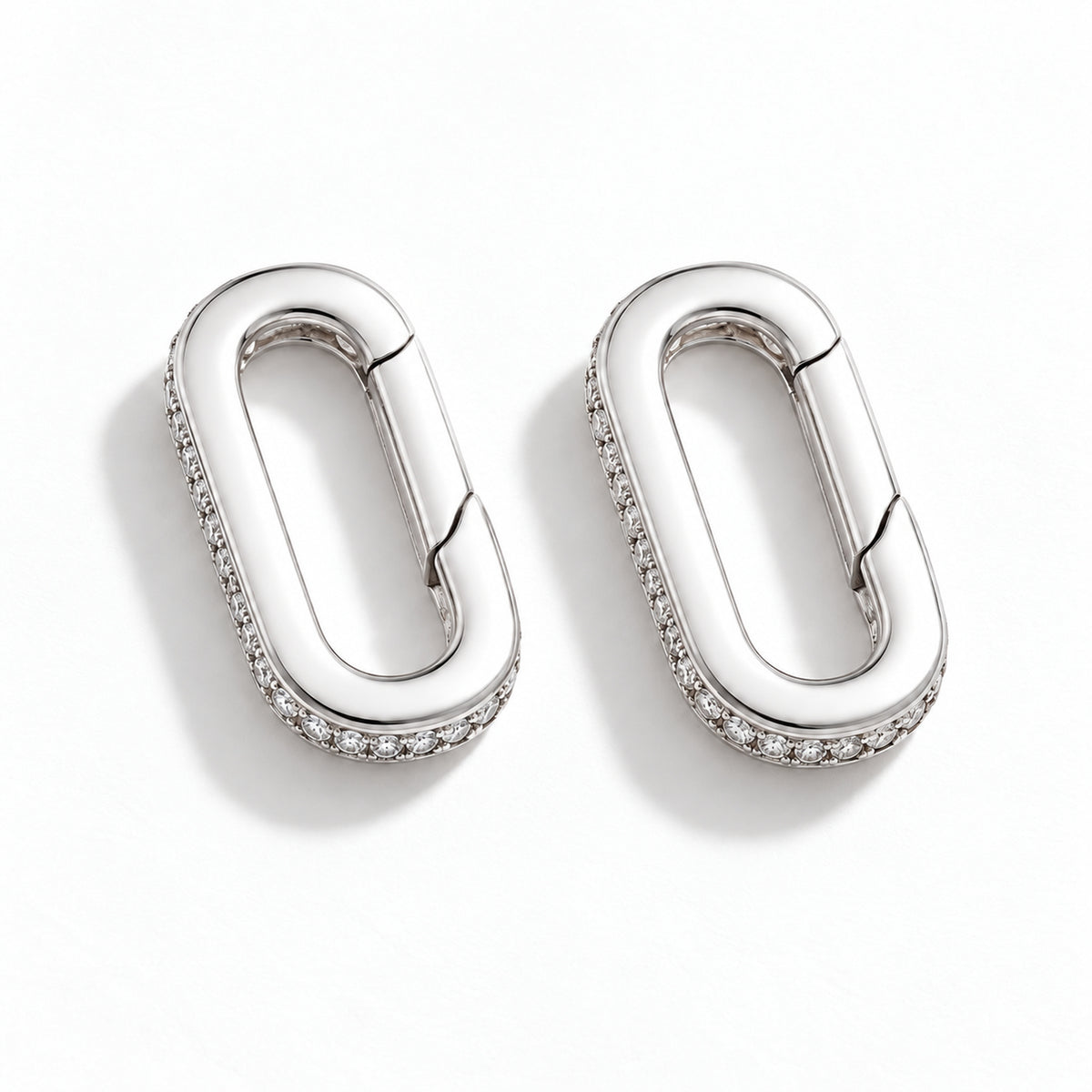 The Strap Converter, two palladium-tone oval spring-gate converters with clear stone detailing, shown as a pair on white.