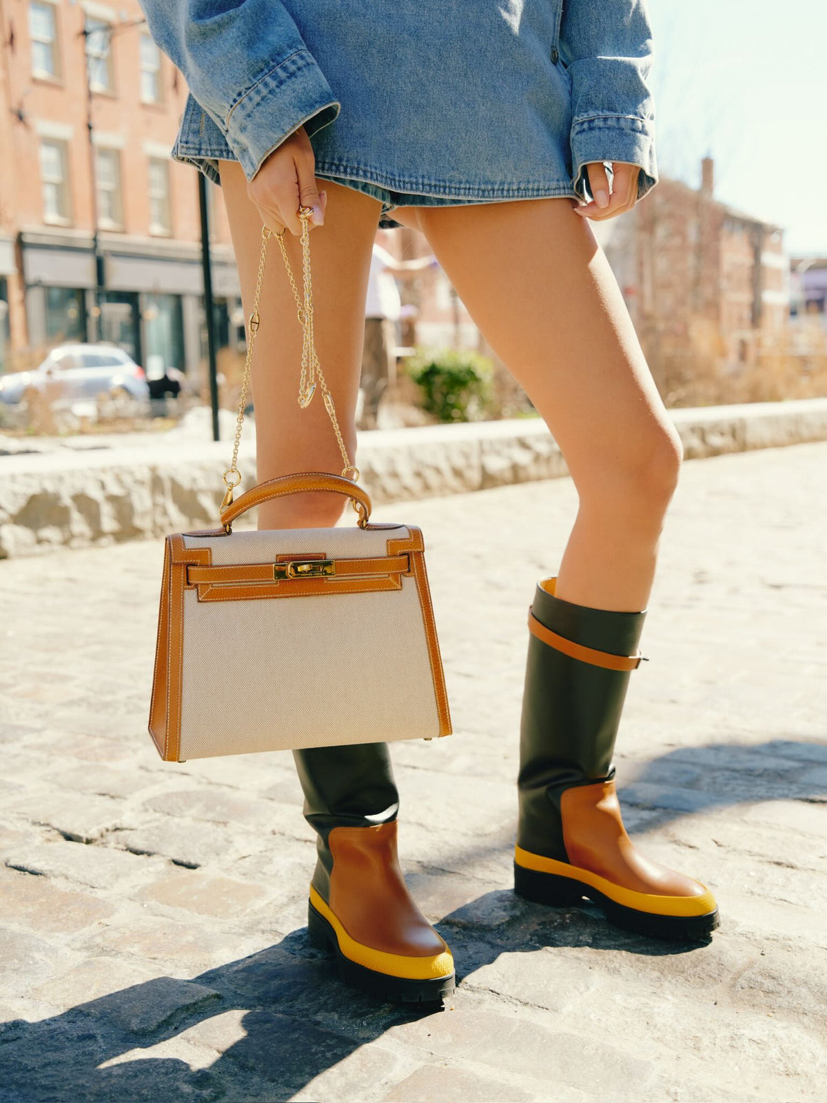 Vintage Hermès Kelly 28 Sellier Naturel and Écru Toile H and Peau Porc Gold Hardware, carried on a chain by a model in boots