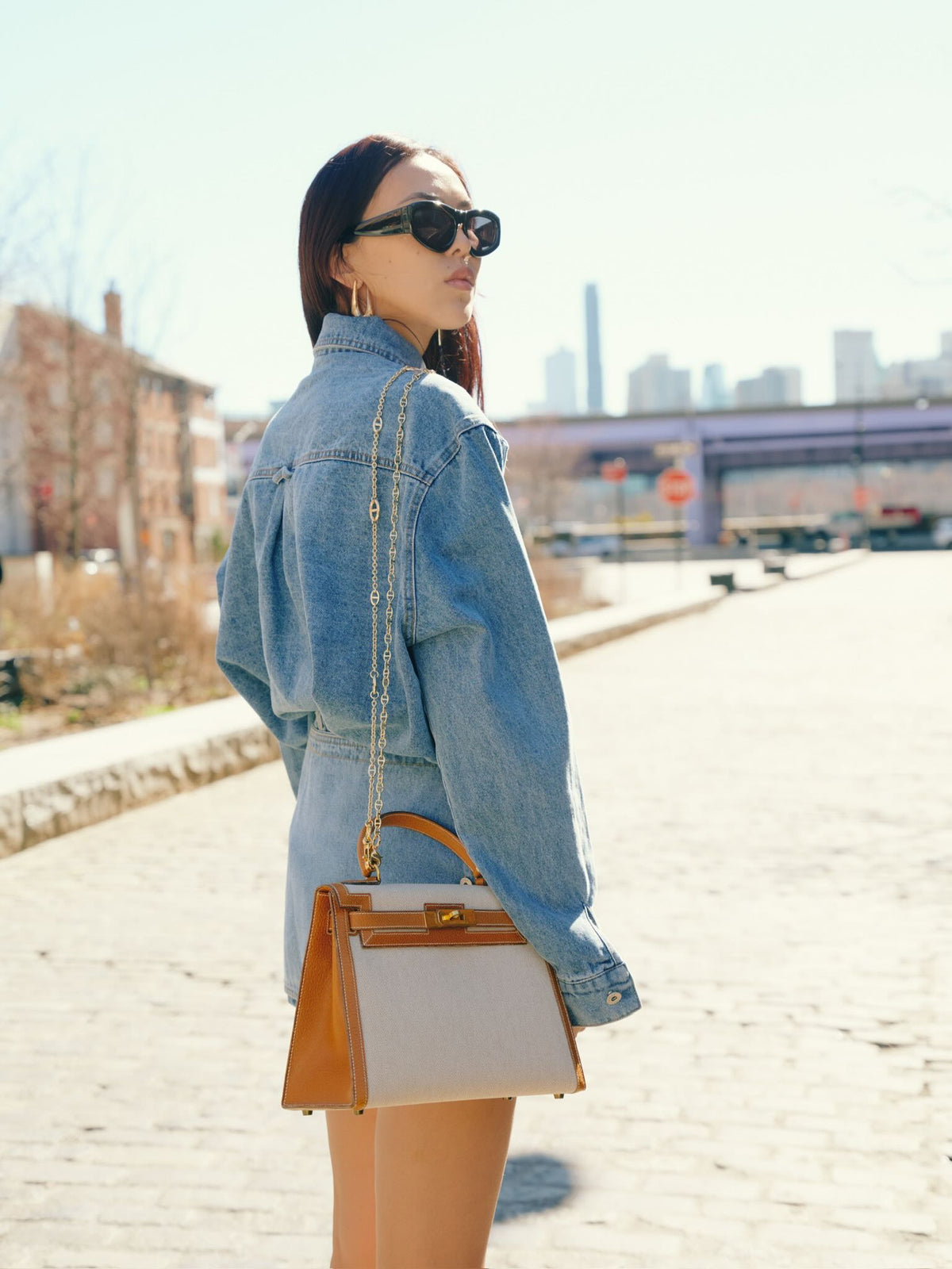 Vintage Hermès Kelly 28 Sellier Naturel and Écru Toile H and Peau Porc Gold Hardware, worn on a chain by a model, rear view of the model