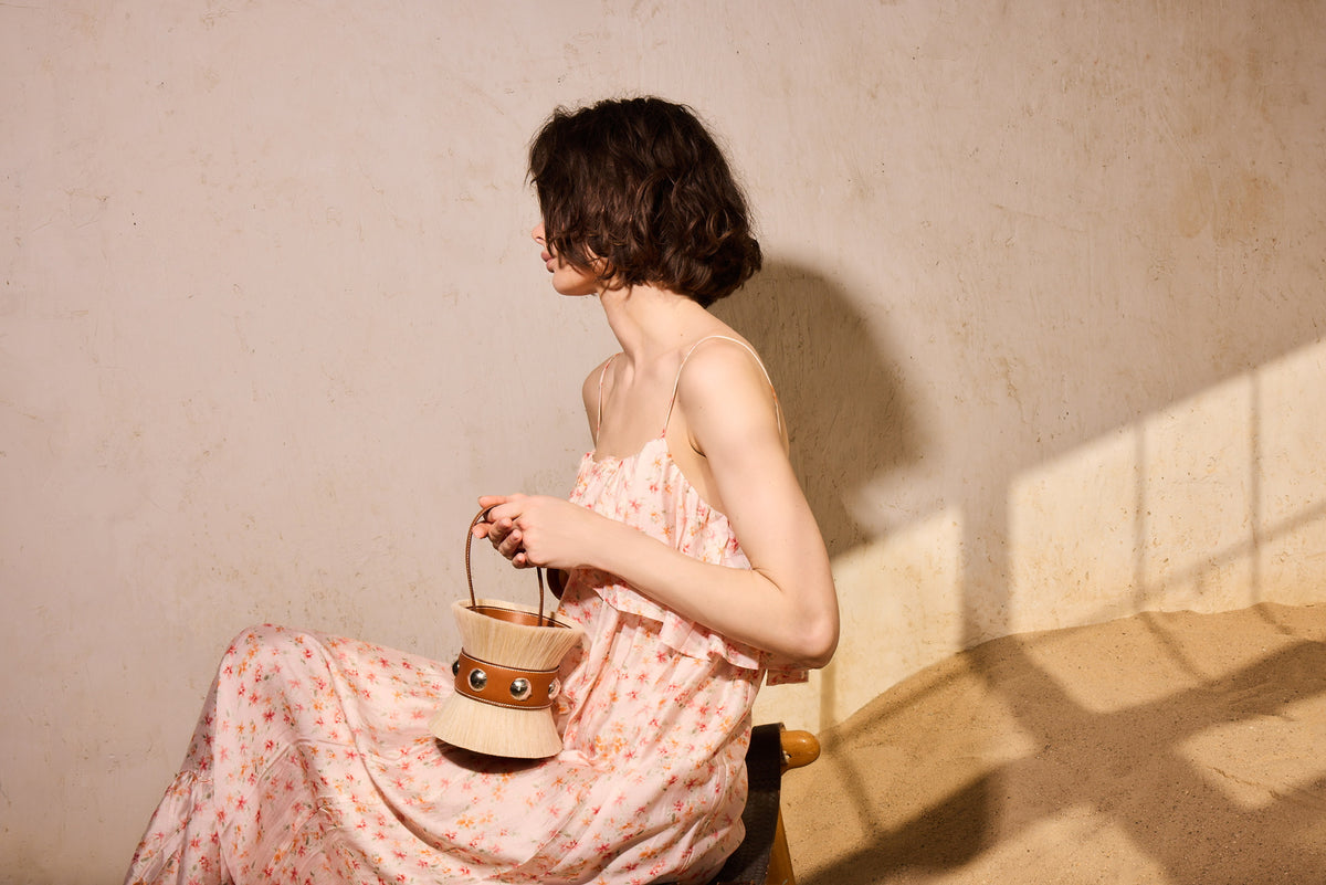 Hermès Mini Médor in horsehair and Barénia with palladium hardware, held by a seated model in a floral slip dress