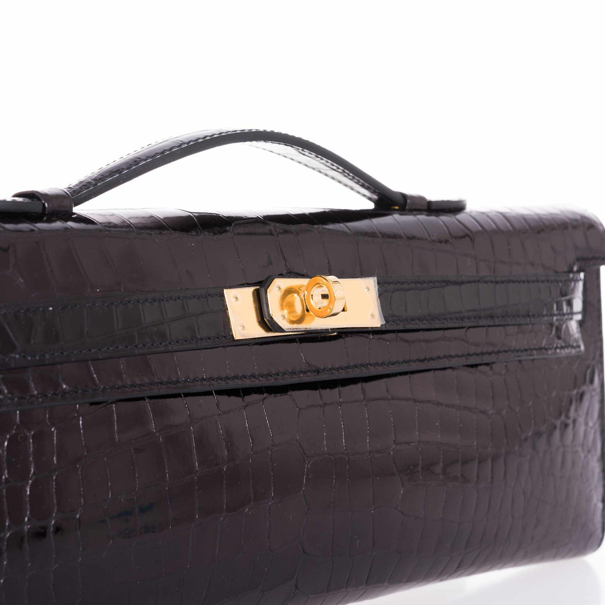 Hermès Kelly Cut Noir Shiny Porosus Crocodile Gold Hardware, close view of the turn-lock and top handle